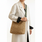 Person holding a beige patterned handbag with a neutral background